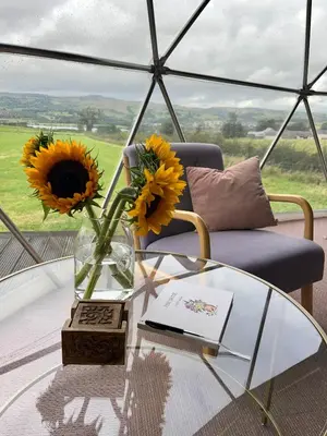 a glass table with a vase of sunflowers on top of a room at The Dome at Midauchengowan in Lochwinnoch