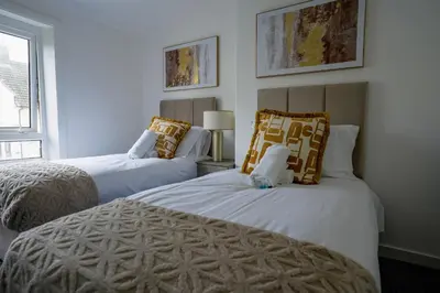 two beds in a room with white walls at Simpson House in Tillicoultry