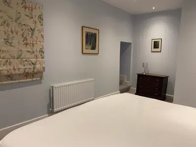 a bedroom with a large bed and a dresser at Bee Cottage in Moffat