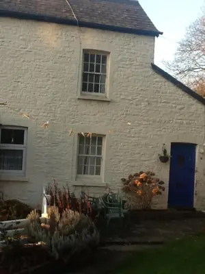a white brick house with a blue door at Bee Cottage in Moffat