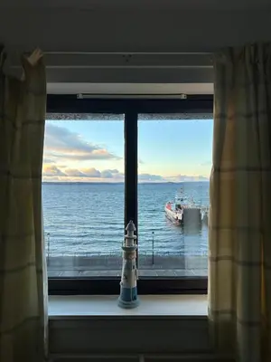 a window with a view of the ocean and a boat at Seaside Penthouse in Largs