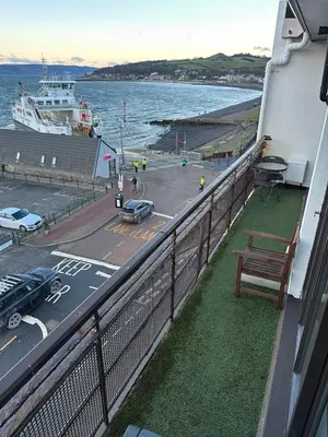 a balcony with a bench and a boat in the water at Seaside Penthouse in Largs
