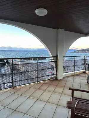 a view of the ocean from a balcony with a bench at Seaside Penthouse in Largs