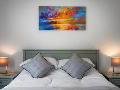 a bed with two pillows and a painting on the wall at A'chrannchuir in Blackwaterfoot
