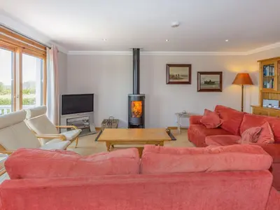 a living room with red couches and a fireplace at Tanglewood in Whiting Bay