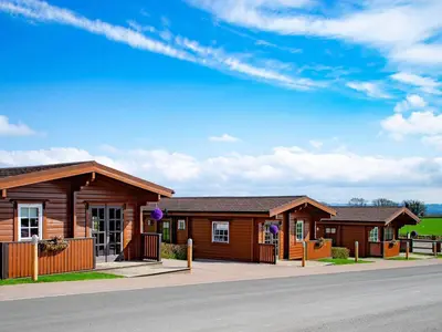 a row of wooden cottages on the side of a road at Lodge 4 - Uk51264 in Glasgow