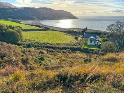 a house on a hill next to the ocean at The Green in Lochranza