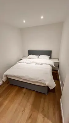 a bedroom with a bed with white sheets and wooden floors at Modern 5 bedroom Getaway Free Parking in Hurlet