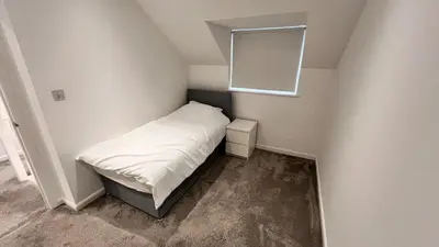 a small bedroom with a bed and a mirror at Modern 5 bedroom Getaway Free Parking in Hurlet