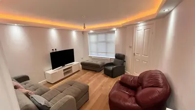 a living room with a couch and chairs and a flat screen tv at Modern 5 bedroom Getaway Free Parking in Hurlet