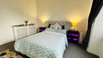 a bedroom with a bed with purple lights on it at Spacious 3 Bedroom Entire Apartment Self Check in & Free Parking in Cowdenbeath