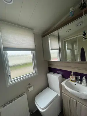 a bathroom with a toilet and a sink and a mirror at Shells at Sandylands in Stevenston