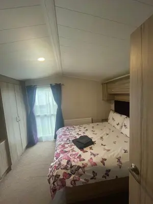 a bedroom with a bed with a floral comforter at Shells at Sandylands in Stevenston