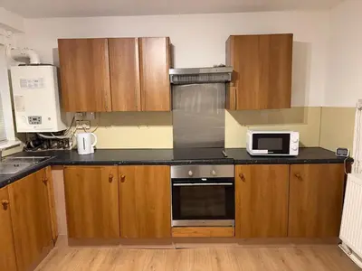 a kitchen with wooden cabinets and a microwave at Acorn Spacious Stay Glasgow in Glasgow
