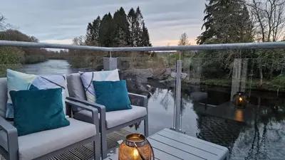a balcony with two chairs and a view of a river at Modern apartment on the river in Callander in Callander