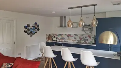 a kitchen with white chairs and a counter with blue cabinets at Modern apartment on the river in Callander in Callander