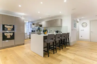 a kitchen with a white counter and stools at Luxury 2BR Park Lane Apartment Mayfair Sleeps 6 PL15B in Moffat