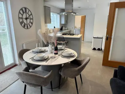 a kitchen with a table with chairs and a clock on the wall at Luxury 4BR Detached Exec Home in Cadzow