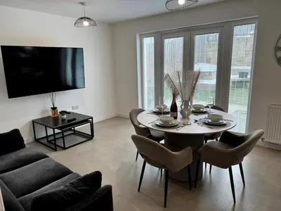 a living room with a table and chairs and a television at Luxury 4BR Detached Exec Home in Cadzow