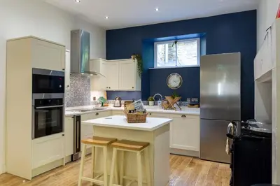 a kitchen with white cabinets and a blue wall at Old Argyll House in Rashfield