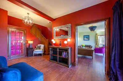 a living room with red walls and a blue couch at Oban Bay Hall in Dunollie