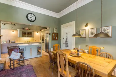 a kitchen and dining room with a wooden table and a clock at Argyll Country House in Clachan