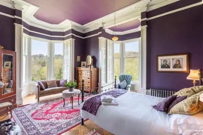 a bedroom with a large bed and purple walls at Argyll Country House in Clachan