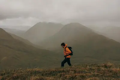 a man walking on the top of a mountain at Auch - Cottages in Bridge of Orchy
