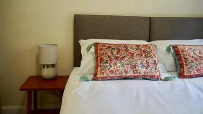 a bed with two pillows and a lamp on a table at Auch - Cottages in Bridge of Orchy