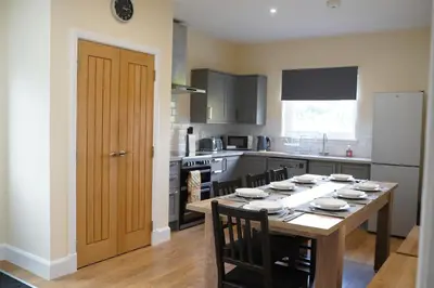 a kitchen with a wooden table with chairs and a refrigerator at Auch - Cottages in Bridge of Orchy