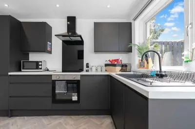 a kitchen with black cabinets and a sink and a window at Contractor & Family Friendly House - Sleeps 8 - FREE Parking and Fast Wi-Fi in Uphall