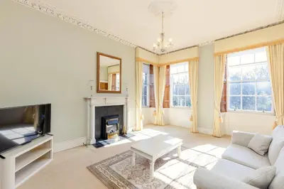 a living room with a couch and a fireplace at Top floor, central, spacious, period apartment with park views in Edinburgh