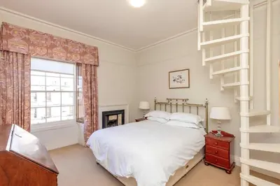 a bedroom with a white bed and a staircase at Top floor, central, spacious, period apartment with park views in Edinburgh