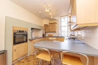 a kitchen with a counter and some chairs in it at Top floor, central, spacious, period apartment with park views in Edinburgh