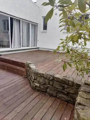 a wooden deck with a stone wall on a house at King size bed Direct bus to city center Silver in Edinburgh