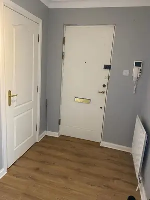an empty room with a white door and wooden floors at Modern central 2 bedroom flat with private parking in Glasgow
