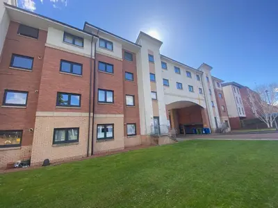 a large brick building with a grass yard in front of it at Modern central 2 bedroom flat with private parking in Glasgow