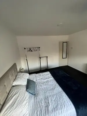 a bedroom with a large bed with a blue pillow on it at Beautiful modern self-contained house in Moffat