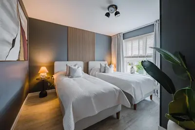 a bedroom with two beds with white sheets and a window at JW Canmore ApartHouse in Glasgow