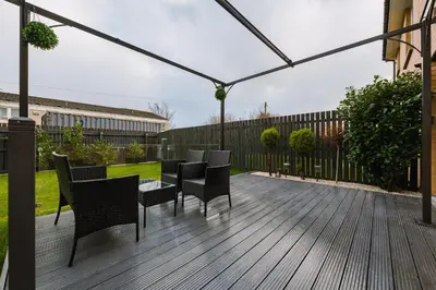 a wooden deck with chairs and a pergola at JW Canmore ApartHouse in Glasgow