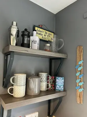 a shelf with cups and books on it at The Beach View - Greenan in Ayr