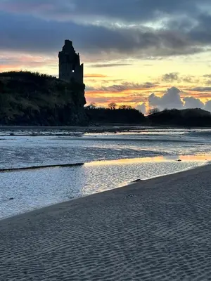 a castle sitting on top of a hill next to the ocean at The Beach View - Greenan in Ayr