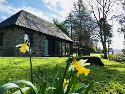a stone house with yellow flowers in front of it at Turbine House in Lochgilphead