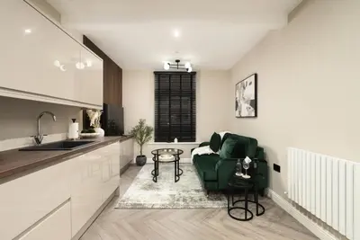 a kitchen with a green chair and a table at South Lane Apartments - City Centre in Edinburgh