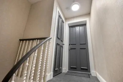 a hallway with a black door and stairs at South Lane Apartments - City Centre in Edinburgh