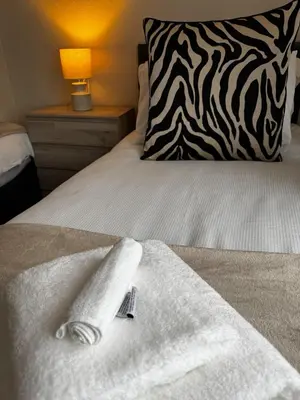 a bed with white towels on it with a pillow at Anchor stays - your steady base away from home in Cambusnethan