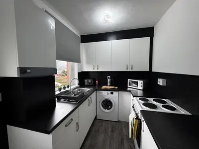 a black and white kitchen with a washer and dryer at Anchor stays - your steady base away from home in Cambusnethan