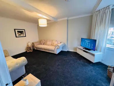 a living room with a couch and a flat screen tv at Anchor stays - your steady base away from home in Cambusnethan