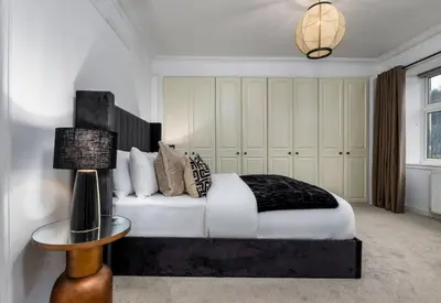 a bedroom with a bed and a lamp and a table at Stirling Edwardian House - Fireplace,Garden,Parking in Stirling