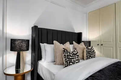 a bedroom with a black and white bed with pillows at Stirling Edwardian House - Fireplace,Garden,Parking in Stirling